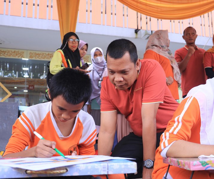 Pj Wali Kota Pekanbaru Muflihun menyaksikan seorang anak sedang menggambar sesuatu dalam peringatan Hari Anak Nasional di lapangan Mal Pelayanan Publik, Kamis (23/11/2023). Foto: Istimewa.
