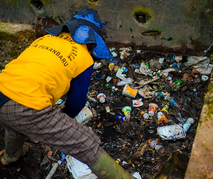 Pasukan kuning Dinas PUPR Pekanbaru membersihkan sampah yang menyumbat drainase. Foto: Istimewa.