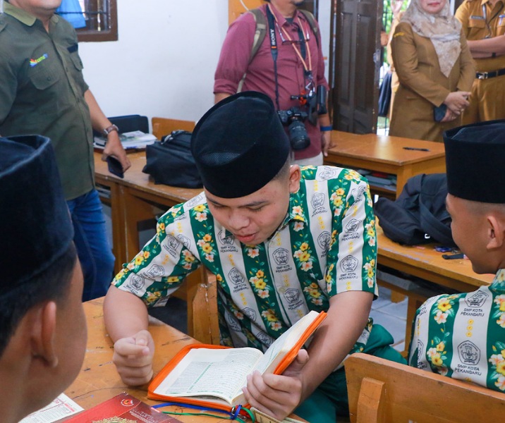 Seorang pelajar SMP Negeri 4 Pekanbaru saat membaca Alquran sebelum jam belajar pada 18 Maret 2025. Foto: Istimewa.