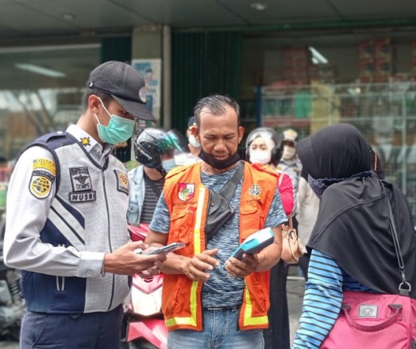 Petugas Dishub Pekanbaru mengenalkan alat bayar non tunai ke juru parkir dan pengendara di halaman Pasar Buah pada 19 April 2021 lalu. Foto: Surya/Riau1.