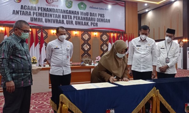 Wali Kota Pekanbaru Firdaus saat menandatangani nota kesepahaman dengan empat universitas dalam mendukung pendirian Politeknik Negeri Pekanbaru pada 25 Juni 2021. Foto: Surya/Riau1.