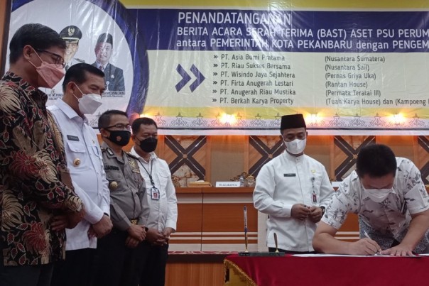 Salah seorang direktur pengembang perumahan menandatangani dokumen penyerahan aset fasum dan fasos ke Pemko Pekanbaru disaksikan utusan dari KPK di Aula Gedung Utama Kompleks Perkantoran Tenayan Raya, Jumat (3/12/2021). Foto: Surya/Riau1.